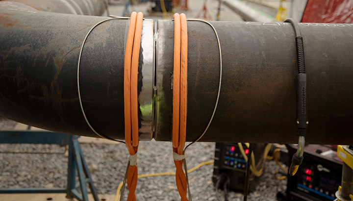 A pipe being heated with orange air-cooled cables