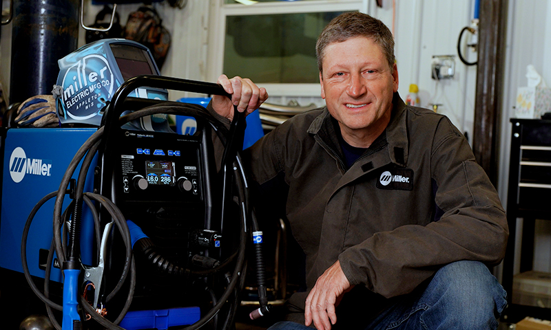 Andy Weyenberg next to a Miller Multimatic 220 AC/DC multiprocess welder