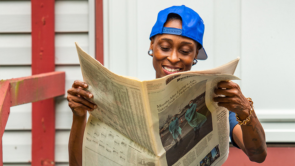 Welding teacher Pa'Trice Frazier reading a newspaper she is featured in about the welder shortage in America