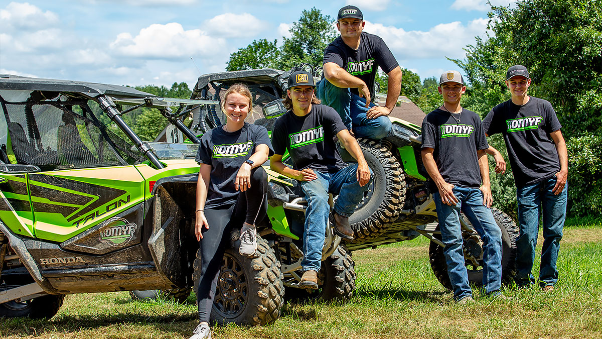 Preston Lewis with members of the Offroad Motorsports Youth Foundation and Baja motorsport racing vehicles outdoors