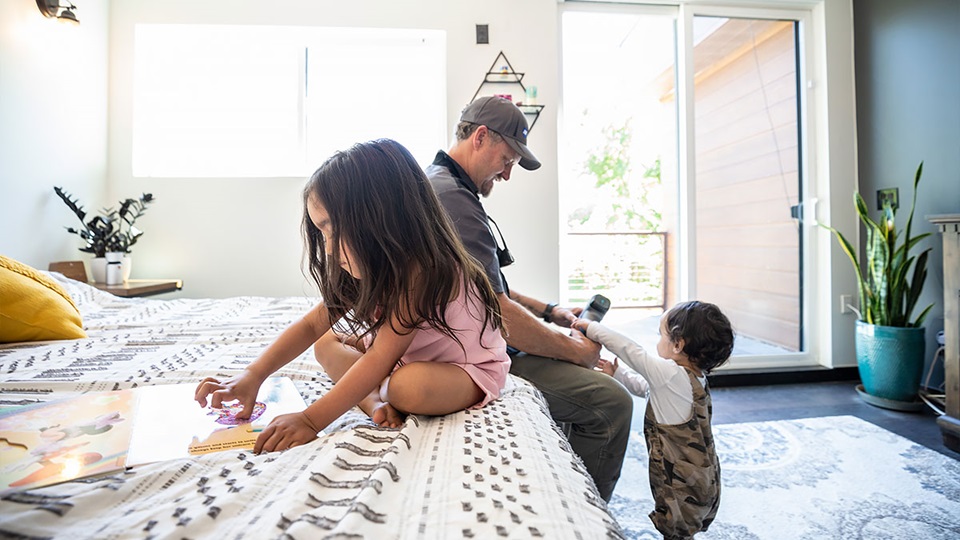 Shane Barber plays with his two young granddaughters inside a home made by welding shipping containers together