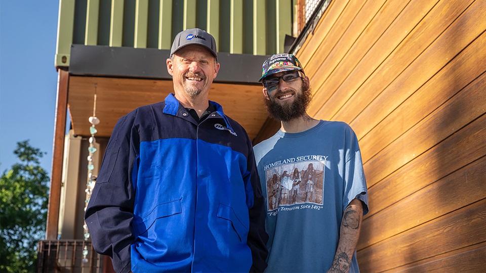 Shane and Cole Barber stand in front of home made by welding shipping containers together