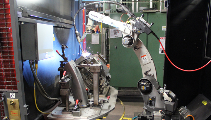 Robot welding part secured in fixture, inside a Miller PerformArc® pre-engineered cell 