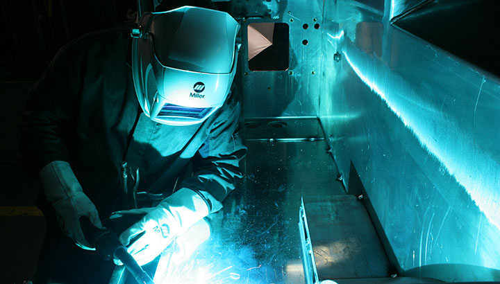 Operator MIG welds aluminum in manufacturing setting