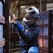 Operator grinding metal wearing welding safety gear