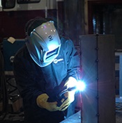 Welding operator welding on vertical metal workpiece