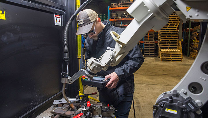 Operator makes adjustments in a robotic welding cell