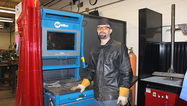 Welding instructor standing next to a Miller LiveArc welding performance management system