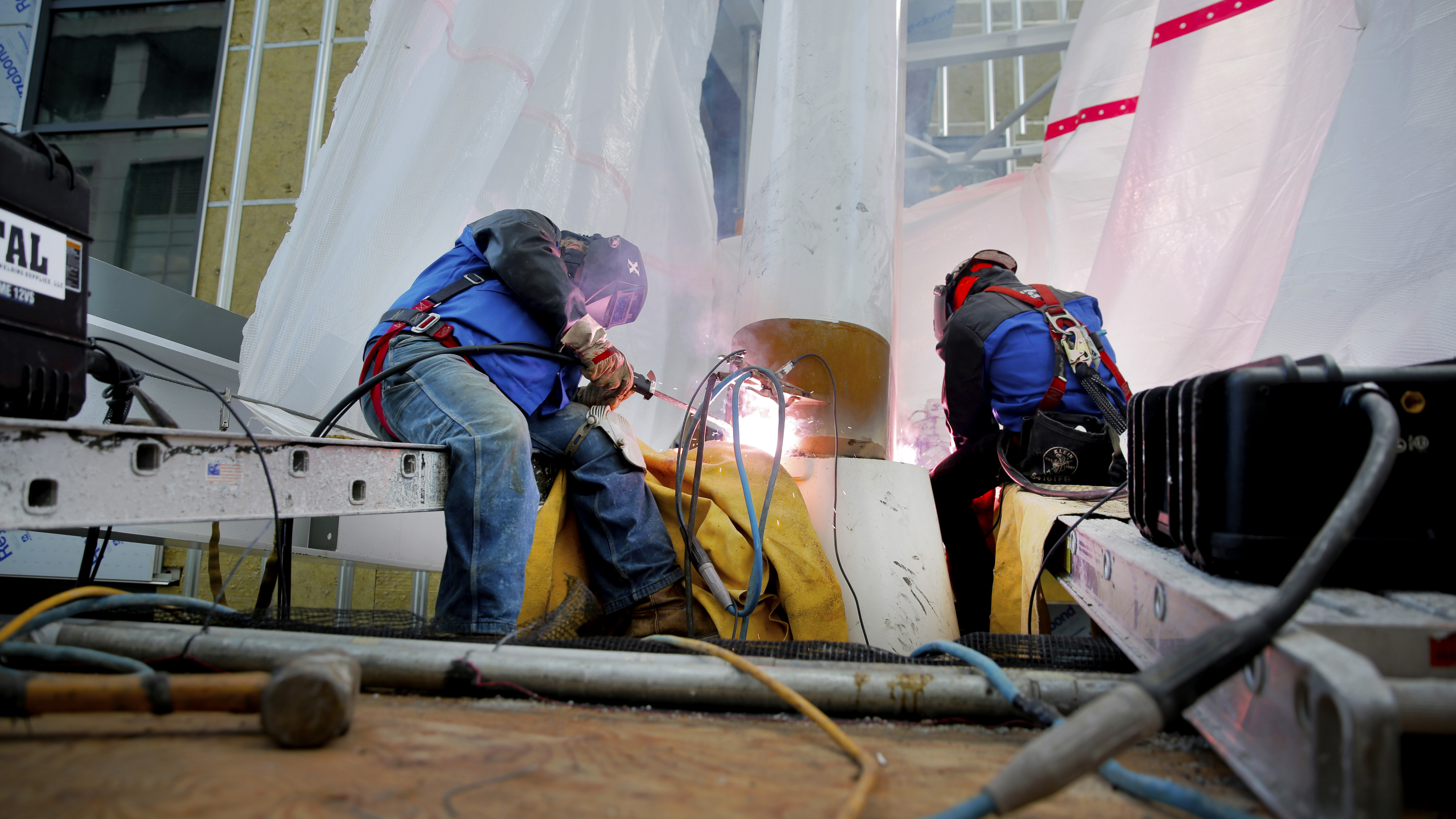Two operators weld on an elevated construction jobsite 
