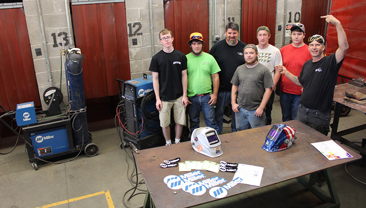 Group photo of students standing in welding lab with Miller power sources