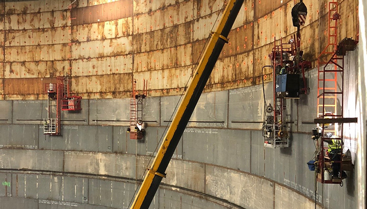 Operators weld the wall inside a large storage tank