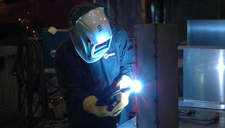 Welding operator welding on vertical metal workpiece
