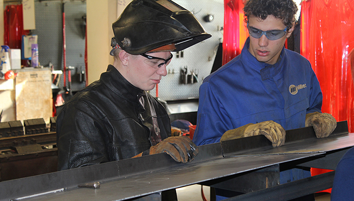 Two students fitting up materials to prepare a weld