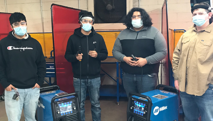 Four welding students pose with Miller welding equipment