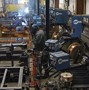 Welding operators in shop with wire feeders mounted at each welding station 