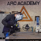 Steve Christena welding in front of Arc Academy sign