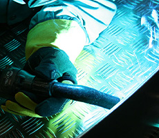 Close-up of a welding gun and operator MIG welding on aluminum