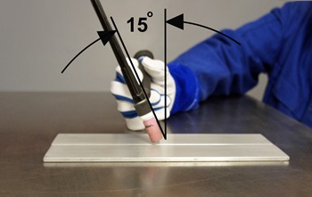 Welder and graphic demonstrating a 15-degree angle between the torch and base metal on a TIG weld