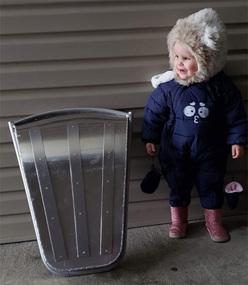 child next to aluminum sled