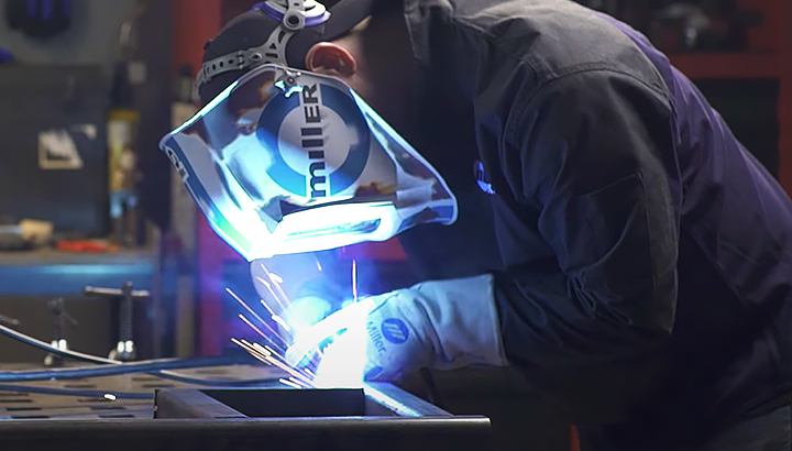 Closeup image of operator MIG welding in a shop