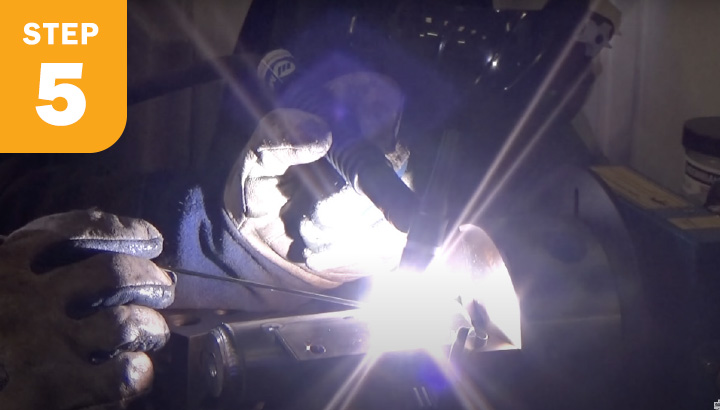 Welder welding to the round tubing.