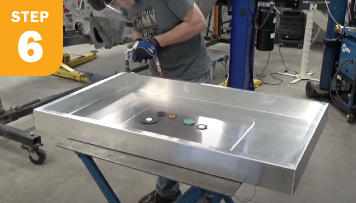 Operator using a small flat disc to smooth the weld surface