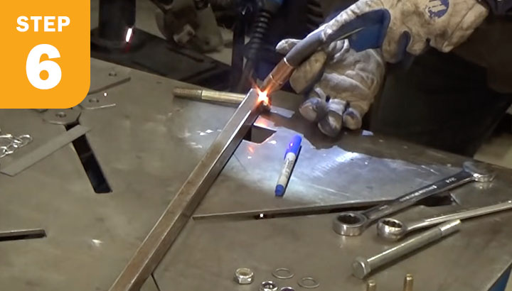 Welder tack welding a bolt to square tubing.