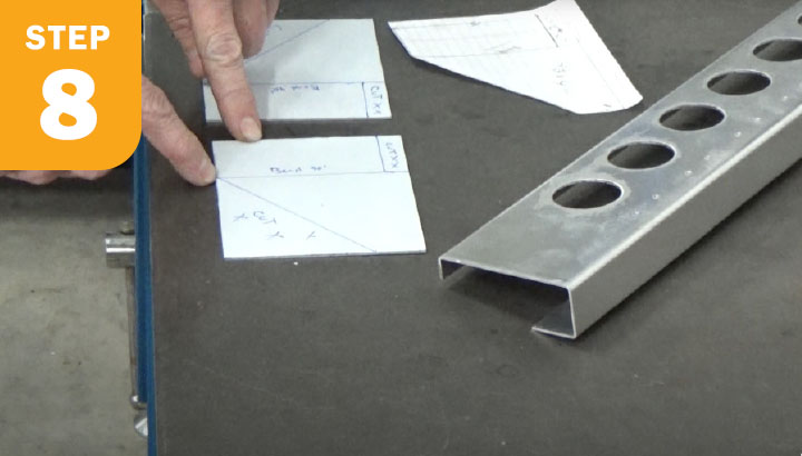 Metal pieces with marked measurements sitting on work bench