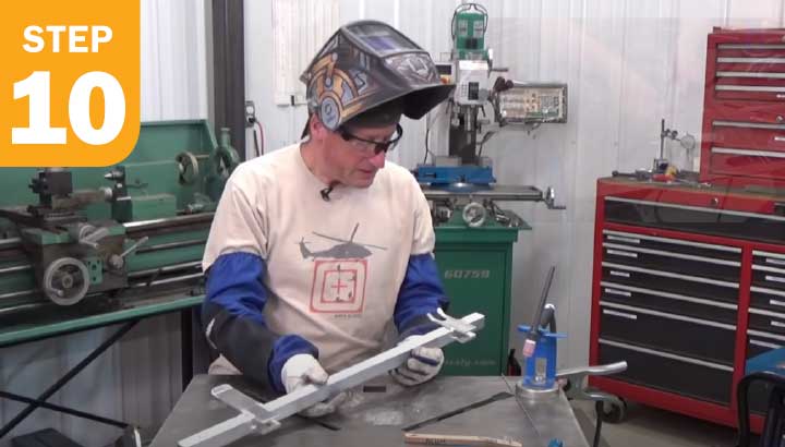 Welder showing the square tubing with the flat stock welded to it.