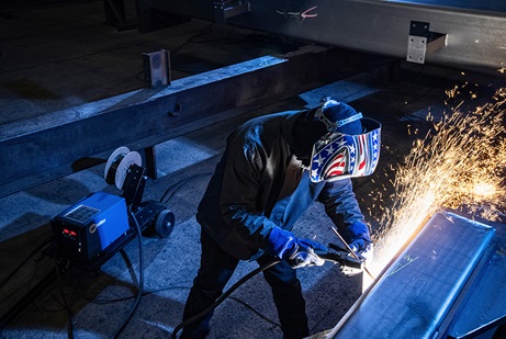 Welder in a shop environment wearing a Miller Helmet.