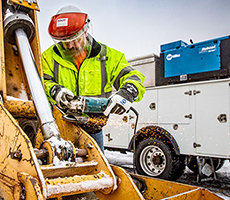 Image of someone grinding. A Miller Bobcat on a work truck is in the background.
