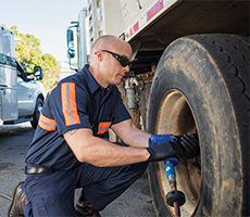 Image of a man using an air compressor on the tire of his work truck