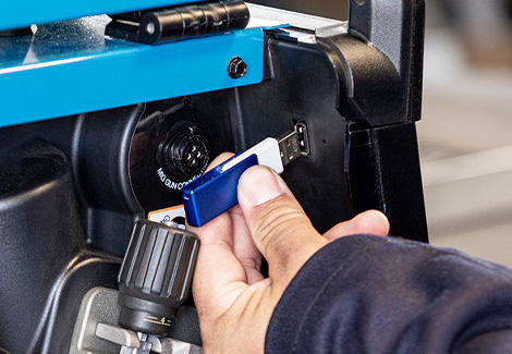 Hand inserting the software update USB drive into the welding machine's USB port.