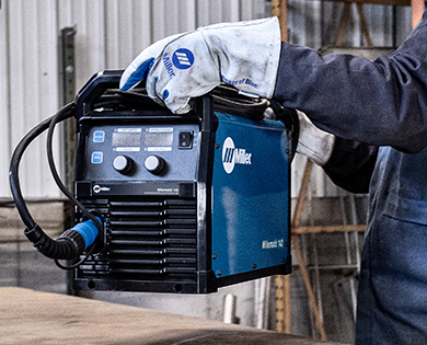 Person in a workshop lifting the Millermatic 142 hobbyist welder.
