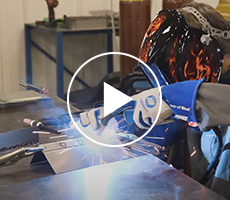Video play icon over an image of a person MIG welding