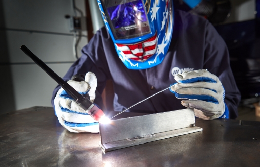 A person TIG welding, using the AC Frequency Control setting on a Miller Syncrowave machine for precise welds