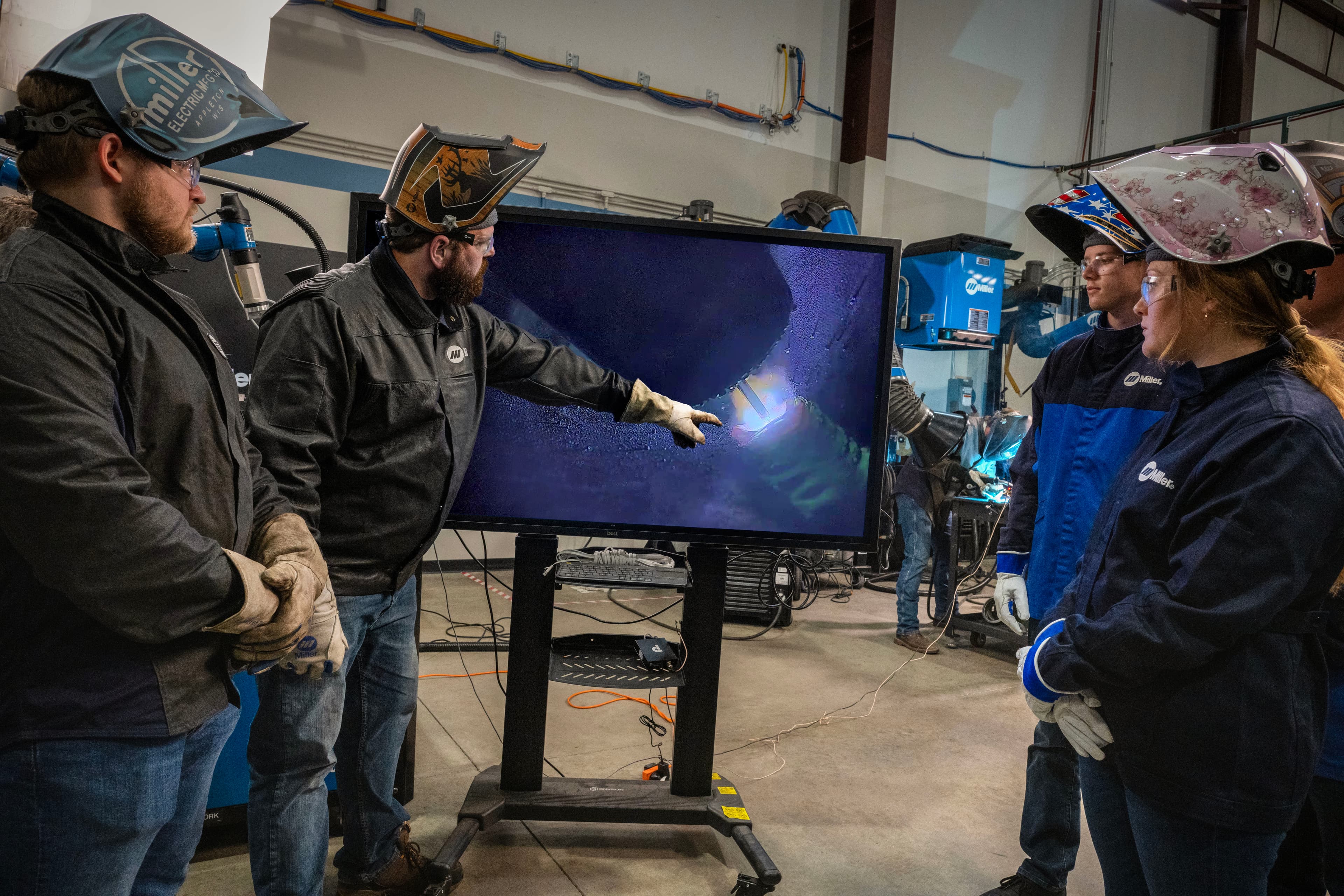 Welding instructor streaming high-definition ArcCapture weld camera system footage on a large screen to students during a hands-on weld training.