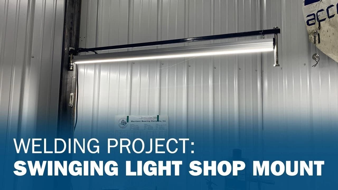 A mounted swinging light fixture attached to a metal industrial wall, with text overlay reading 'Welding Project: Swinging Light Shop Mount'.