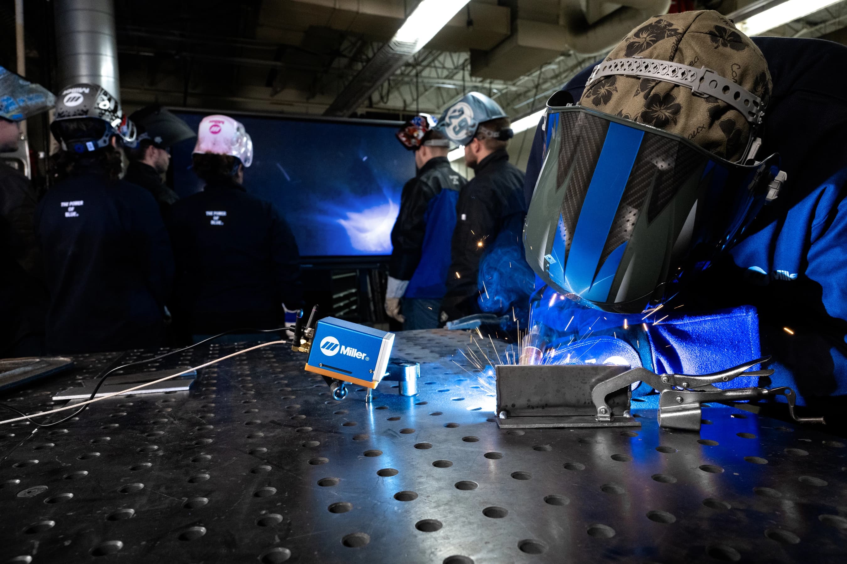 Welding students watching the Miller AcrCapture camera feed on a monitor