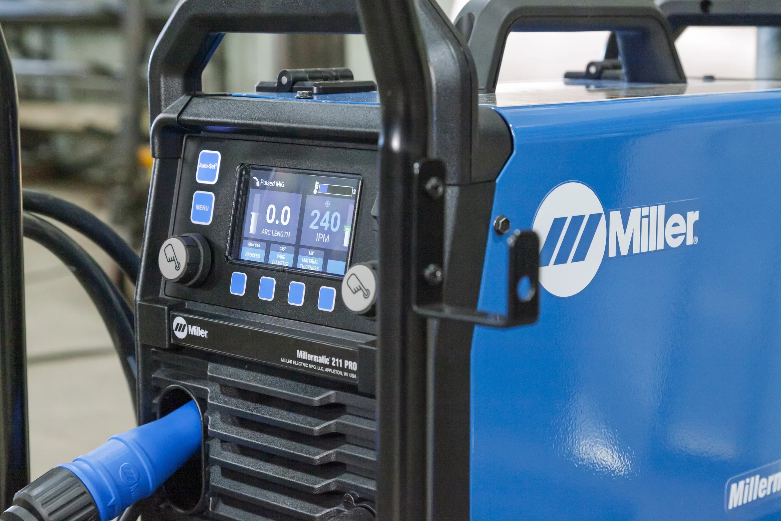 Close-up of a Millermatic 211 PRO welding machine displaying its control panel and settings.